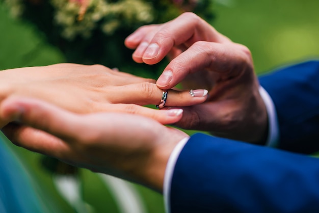 Novio pone a la novia un anillo de bodas de oro blanco en su dedo