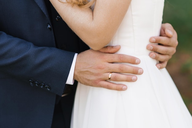 El novio pone su brazo alrededor de la cintura de la novia Primer plano de su mano con un anillo de compromiso