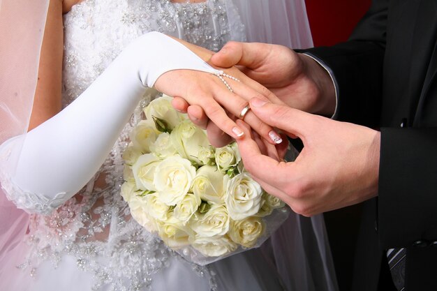 Novio poniendo anillo de bodas en el dedo de la novia