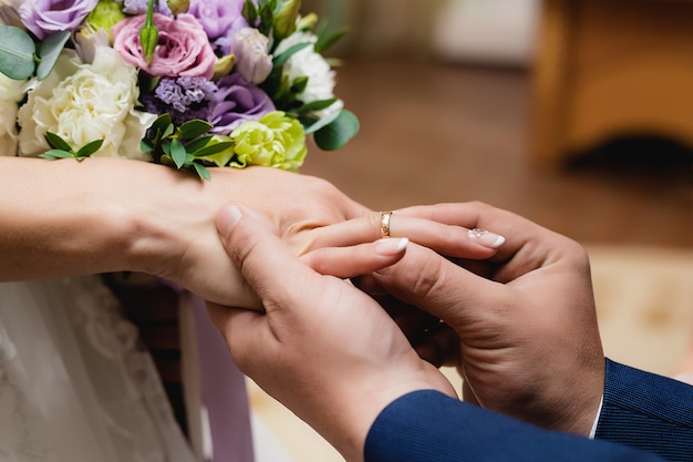 Novio poniendo el anillo en la mano de la novia