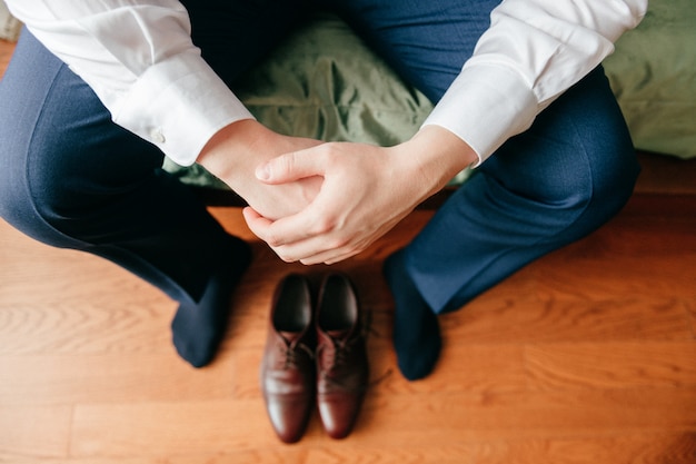 Novio preparándose en la mañana. Prepare las manos, piernas y zapatos de cerca desde arriba