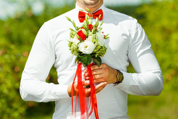 Novio con ramo de boda en manos