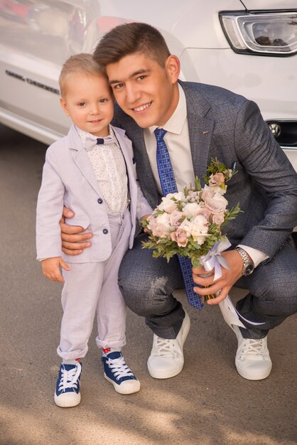 Novio con ramo y niño abrazando el día de la boda