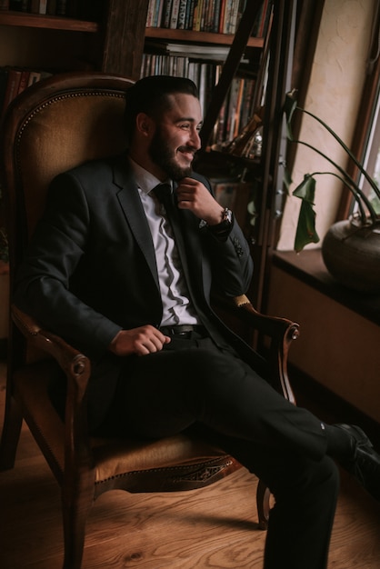 Foto novio sentado en una silla en la biblioteca