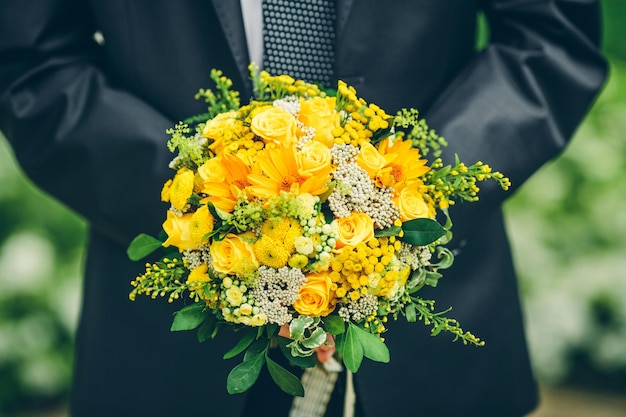 Novio sosteniendo un ramo de girasoles y rosas sin rostro