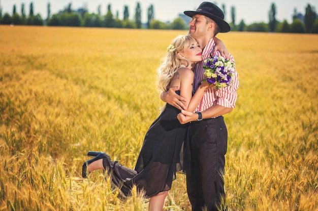 Novio sosteniendo a su novia en el campo de trigo de verano