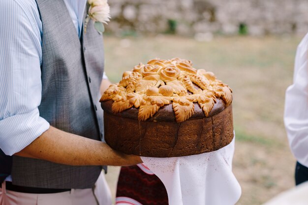 El novio sostiene un pan de boda en un primer plano de toalla