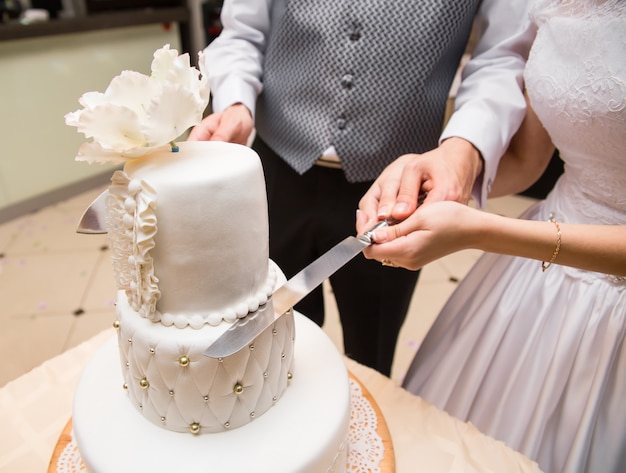 Foto novio tiene mano de novia para cortar un pastel