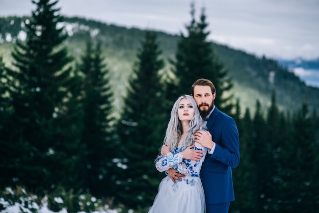 Novio en traje azul y novia en blanco, bordado con patrón azul