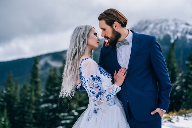 Novio en traje azul y novia en blanco, bordado con patrón azul