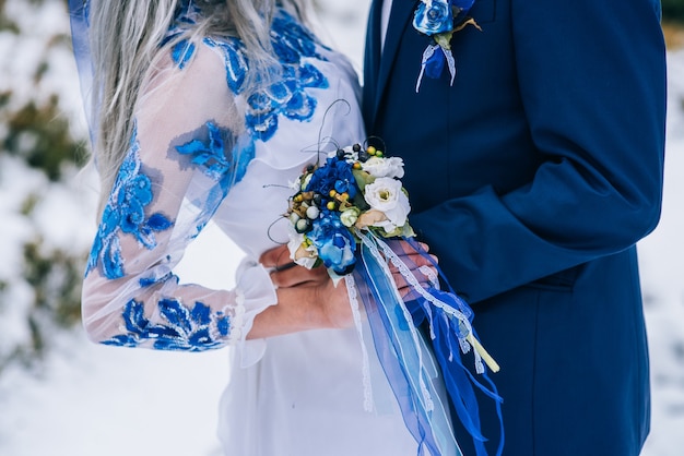 Foto novio en traje azul y novia en blanco, bordado con patrón azul