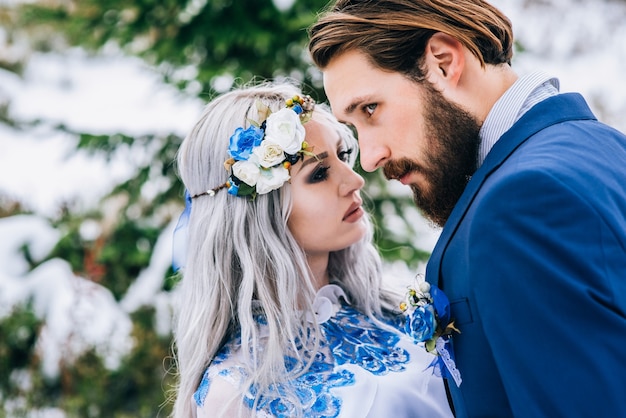 Novio en traje azul y novia en blanco, bordado con patrón azul