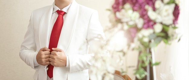 Novio en traje blanco sosteniendo el anillo de bodas