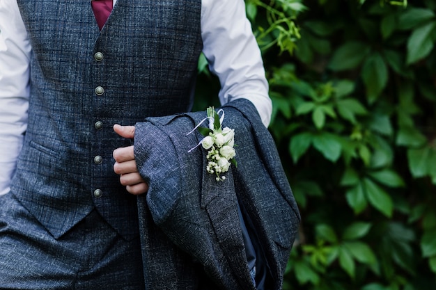 El novio de traje. un hombre con un chaleco sostiene una chaqueta en sus manos