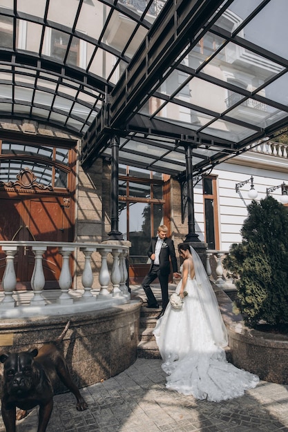 el novio con traje negro y la novia con vestido blanco se paran a la entrada del palacio