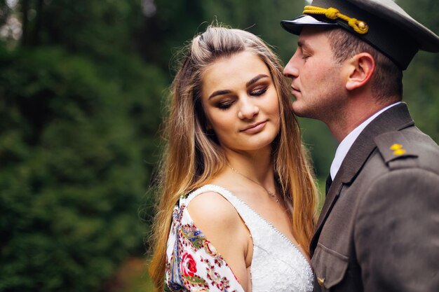 Novio en uniforme militar besando a la novia y ella dobla su espalda w