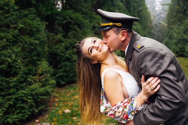 Novio en uniforme militar besando a la novia y ella dobla su espalda w