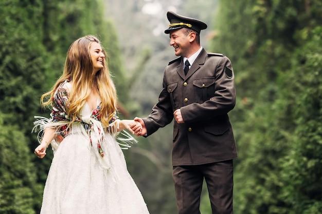 El novio con uniforme militar y la novia con vestido de novia se toman de la mano