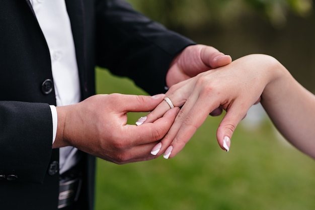 El novio viste el anillo de bodas de la novia en la mano.