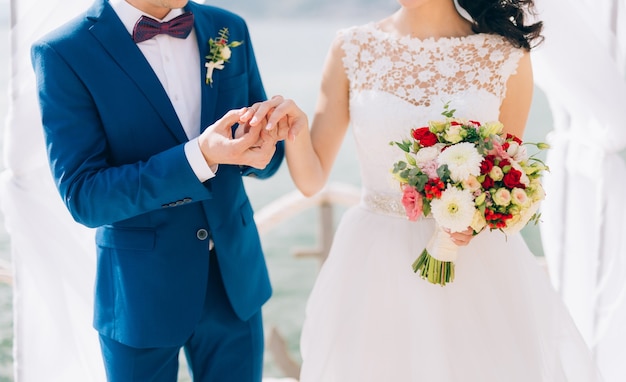 El novio viste un anillo en el dedo de la novia en una ceremonia de boda.