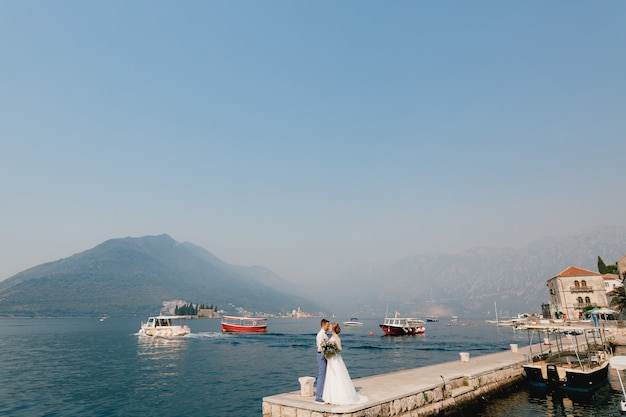 Los novios se abrazan en el muelle cerca del casco antiguo de perast