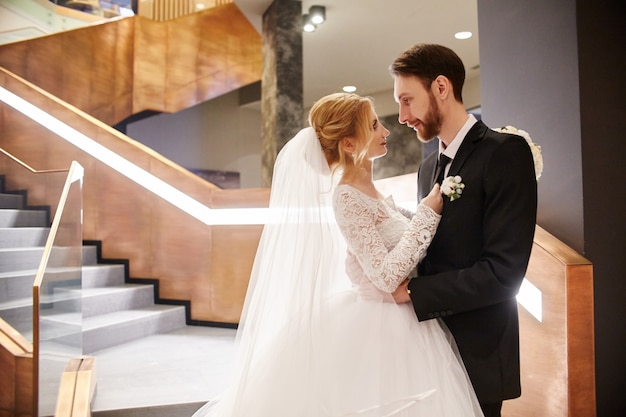 Novios abrazándose y besándose, el primer día de vida juntos. Novia y novio después de la ceremonia de boda, hermosa pareja se ama y abraza