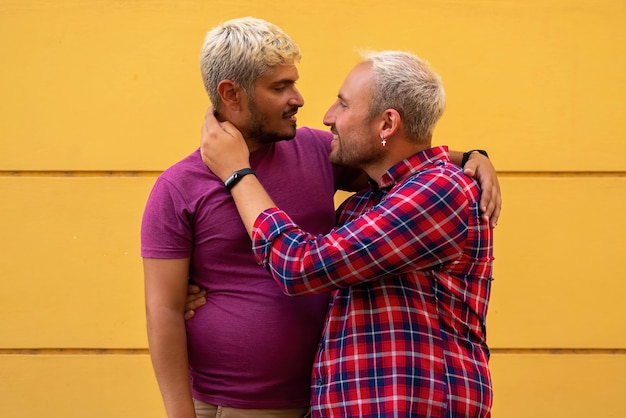 Foto novios abrazándose junto a la pared amarilla