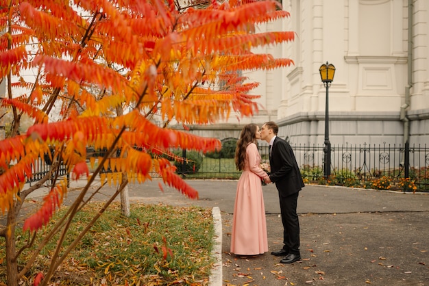 Novios abrazos en la ciudad vieja en otoño. Muros de piedra de la antigua iglesia.