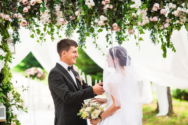 Novios bajo el arco de flores en la ceremonia de boda