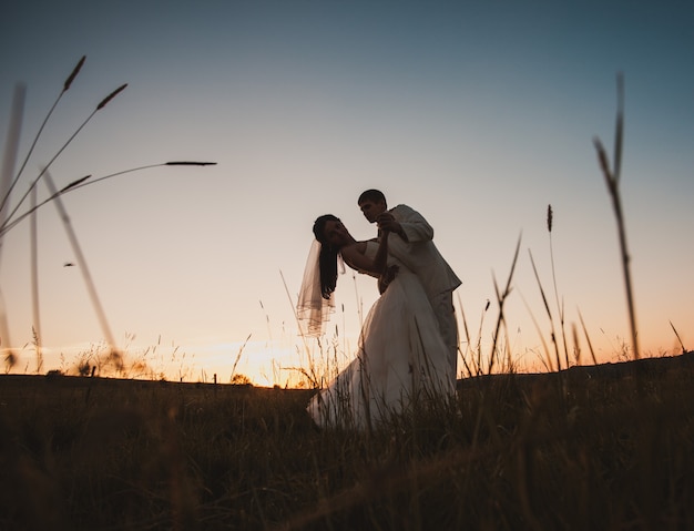 Novios bailando en la colina de la montaña al atardecer