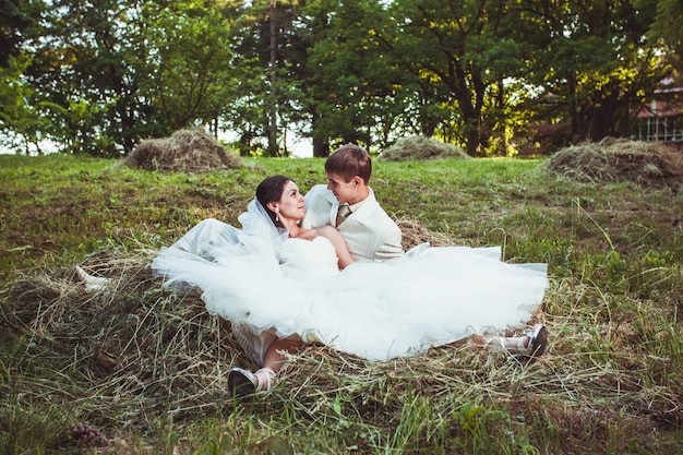 Foto novios se besan y sonríen al aire libre