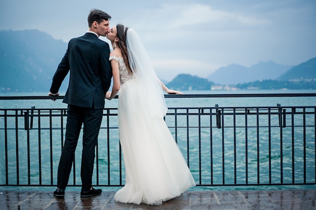 Novios besándose en el fondo de un lago y montañas