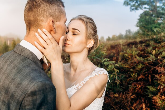 Novios en un bosque en las montañas al amanecer