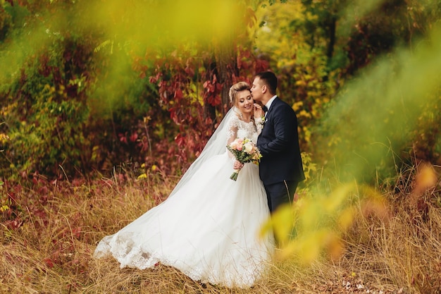 Novios en un bosque en otoño con hojas de naranja