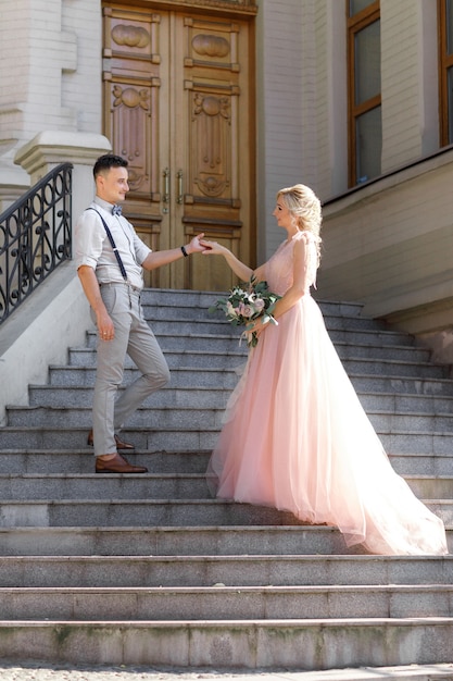 Novios en la ciudad en un día soleado de verano. la novia y el novio abrazándose en las escaleras