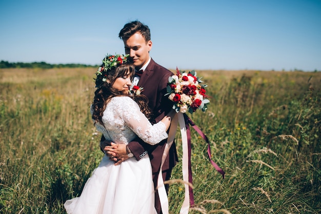 Novios elegantes posando juntos al aire libre en el día de la boda