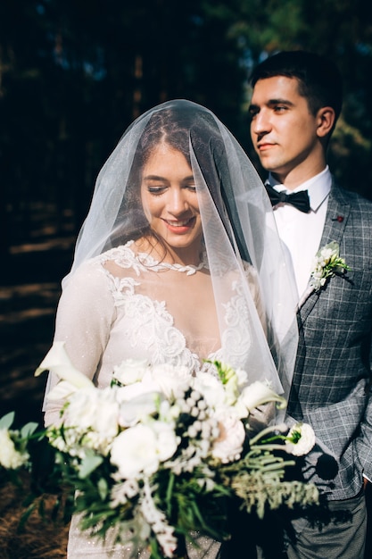 Novios elegantes posando juntos al aire libre en el día de la boda