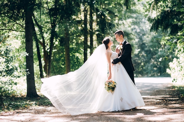 Novios elegantes posando juntos al aire libre en el día de la boda