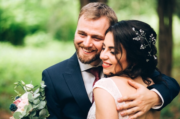 Foto novios elegantes posando juntos al aire libre en el día de la boda