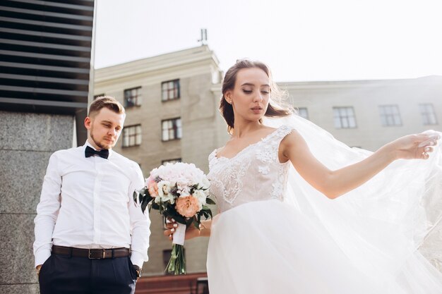 Novios elegantes posando juntos al aire libre en el día de la boda