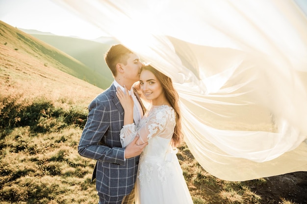 Los novios felices están caminando en las montañas