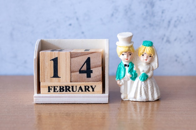 Novios en miniatura con calendario de madera el 14 de febrero. Día de San Valentín