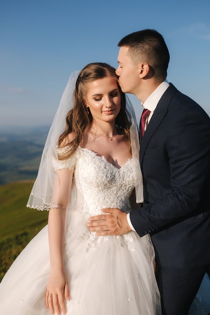 Novios en las montañas. Novios de pie en la colina