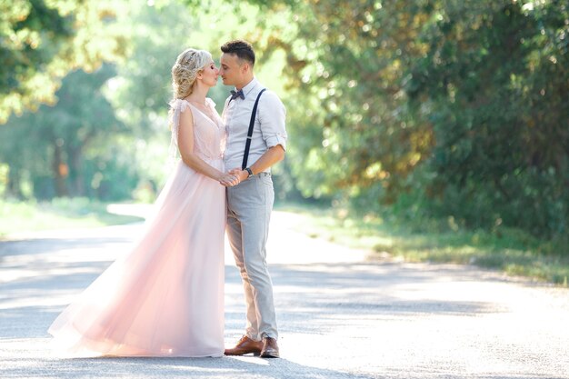 Novios en la naturaleza en día de verano. la novia y el novio abrazándose en la boda. juntos para siempre