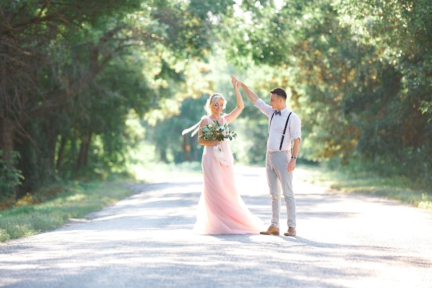 Novios en la naturaleza en día de verano. la novia y el novio bailando