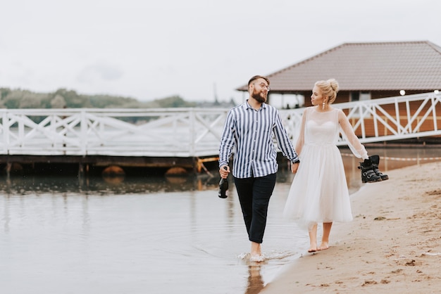 Los novios pasean descalzos por el lago y se dan la mano.