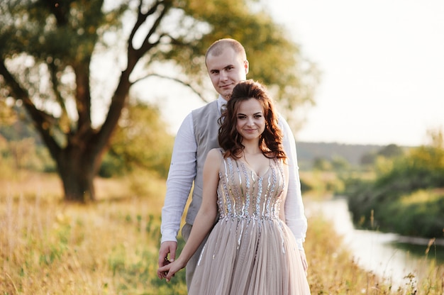 Novios posando en el campo cerca del río