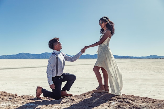 Novios posando en un paisaje blanco con vestido y traje