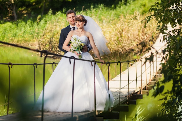 Novios en el puente sobre el río en verano