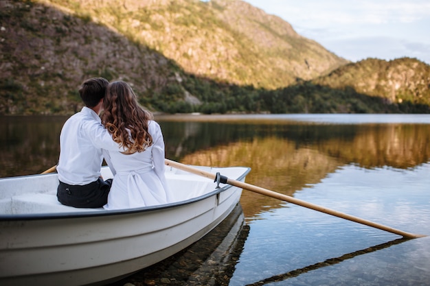 Foto novios sentados abrazando en un bote en el lago